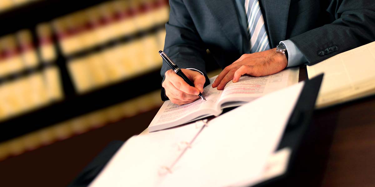 A hand signing a document with a pen